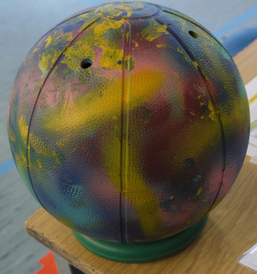 Ein bunt bemalter Goalball steht auf einem Tisch.