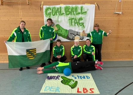 Gruppenfoto der Schulmannschaft, mit der Flagge des Freistaates Sachsen und 2 Bannern: "Goalballtag" sowie "Wir sind Fans der LBS"