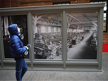 Phillip betrachtet eine historische Fotografie des Innenraumes der Schoenherr-Fabrik.