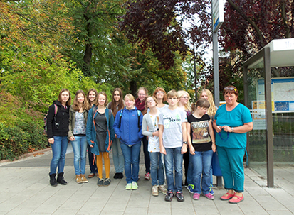Alle dreizehn Schüler und Frau Häusler stehen als Gruppe, die bei der Veranstaltung zur Woche des Sehens zusammengekommen sind, für ein gemeinsames Abschlussfoto neben der Bushaltestelle.