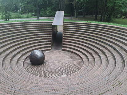 Ringförmige Treppen richten den Blick auf die steinerne Kugel im Mittelpunkt des Denkmals.