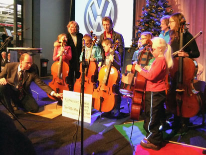 Ein Mann hält den großen Spendengutschein für ein Foto vor die Cello-Mäuse und Peter Maffay.