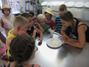 Die Kinder stehen um einen Teller mit warmen Frischkäse.