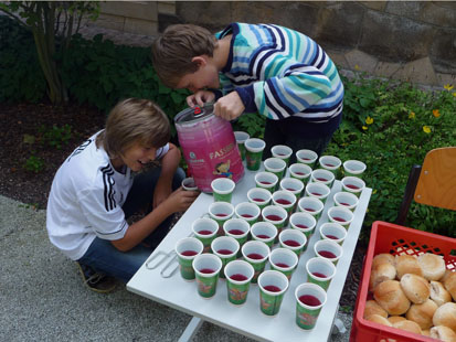 Zwei Jungs füllen Becher mit Fassbrause.