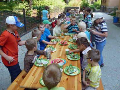 Die Kinder sitzen um einen Tisch und essen Obst.