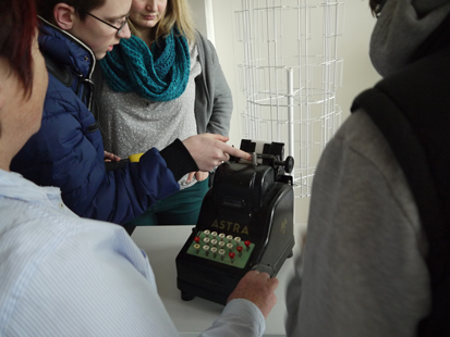 Ein Schueler probiert eine alte Buchungsmaschine der Firma Astra aus.