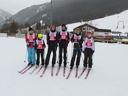 Unsere 6 Sportler kurz vor dem Einzelstart im Skilanglauf mit Ski und nummeriertem Lauftrikot.