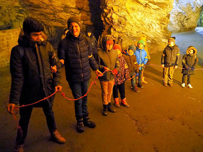 In der Höhle probieren die Kinder eine Übung mit einem Seil aus. In einer langen Reihe stehen sie hintereinander. Im Seil sind viele Knoten für eine besseren Orientierung.