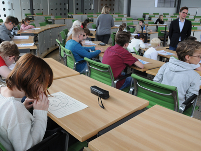 Die im Landtag sitzenden Schüler der Klassenstufe 5 bis 7 betrachten die auf dem Tisch liegende Abbildung und hören zu, was dazu erklärt wird.