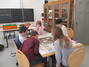 Fünf Schüler aus der Klasse 5 sitzen um einen Tisch herum und spielen Monopoly.