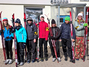 Sieben junge Sportler stehen mit ihren Langläufern in freudiger Erwartung vor der Skihalle.