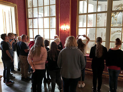Eine Museumsführerin steht vor einer Schülergruppe und erklärt etwas.