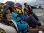 Michael, Leonie und Frau Lehmann sitzen ganz warm eingepackt im Segelboot und fahren bei kräftigem Wind mit Herr Behrendt auf dem Wasser.