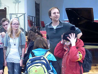 Der Pianist Herbert Schuch steht in einer Gruppe von Kindern.