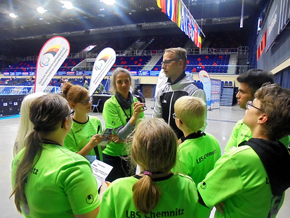 Die Schüler und Frau Bitterlich stehen im Halbkreis um den Goalballer Oliver Hörauf und interviewen ihn.