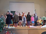 Auf der Bühne singen kostümierte Grundschulkinder von den Tieren in der Waldschule