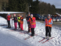 Die Skischüler stehen nebeneinander und hören den Hinweisen des Lehrers zu.