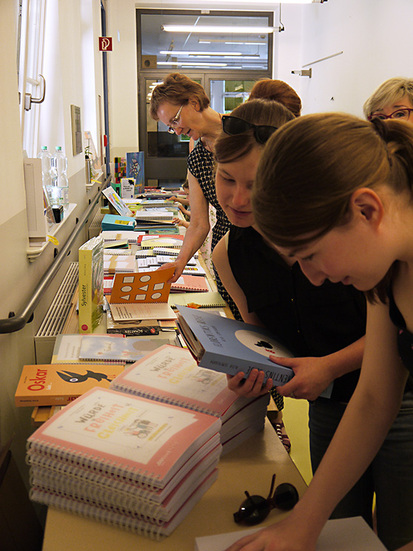 Zwei Schülerinnen und eine Lehrerin betrachten angeregt die Vielzahl an angebotenen Büchern auf dem Büchertisch der DZB lesen.