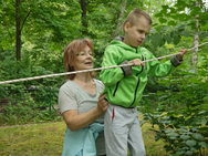 Frau Biebl hilft dem kleinen Max beim Balancieren auf der Slackline.