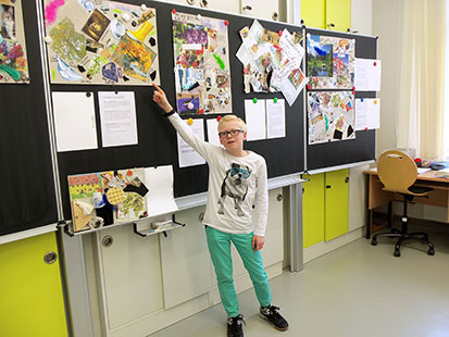 Oliver aus der 5. Klasse erklärt vor der Wandtafel eines Klassenzimmers die angebrachten Schülerplakate.