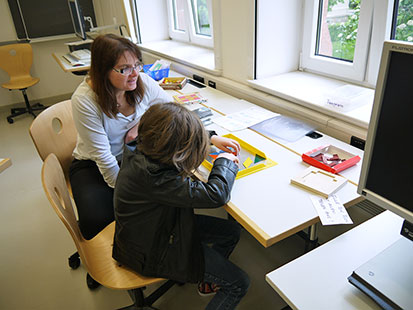 Im Mathezimmer erklärt Frau Hötzeldt ein Spiel mit verschiedenen geometrischen Magnetplättchen.