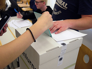 Ein Schüler wirft den Wahlschein in die Wahlurne.