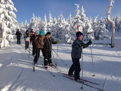 Kinder sind auf Langlauf-Ski unterwegs.