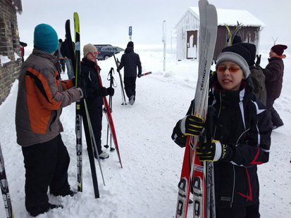 Kinder halten ihre Ski in der Hand.