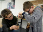 Zwei Schüler spinnen mit einer Spindel Wolle zu Garn.